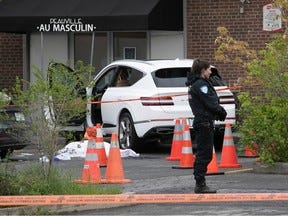 Montreal police stand guard next to body of a woman who was shot dead in her car on Tuesday in Côte-des-Neiges. The car rolled into a building after the shooting, and projectile holes were found in the side window.