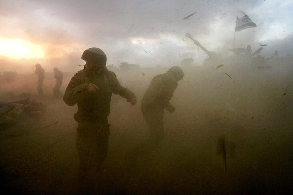 Israeli gunners react as they stand in the shock wave as an artillery piece fires into southern Lebanon from a position near Kiryat Shmona, northern occupied Palestine, in this July 14, 2006 file photo. (AP)