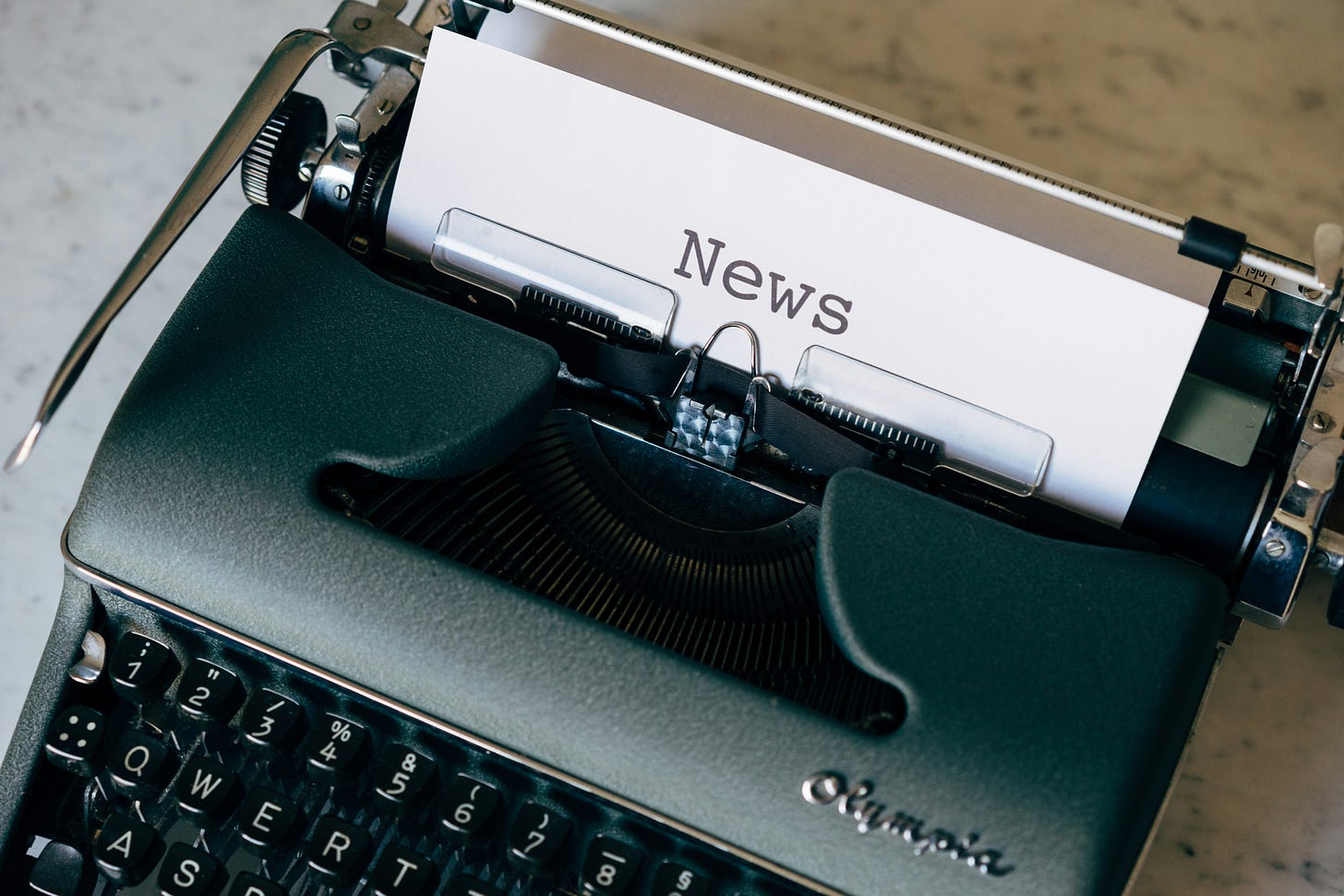 Image of a typewriter and a piece of paper that says "news."