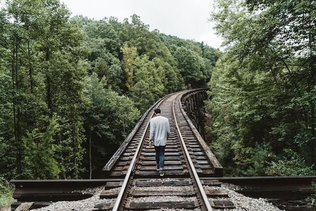 Man walking down a raised railway.
