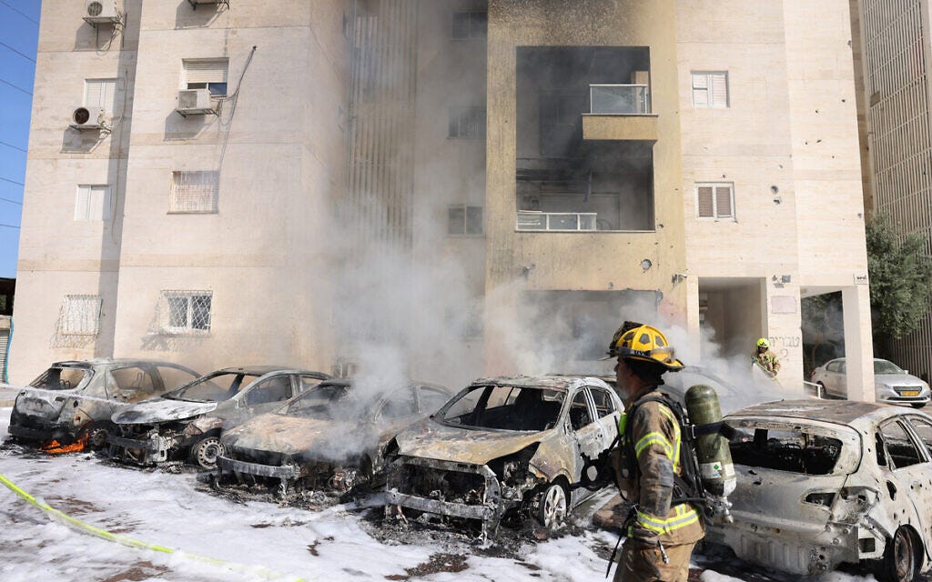 Israeli fire brigade teams douse the blaze in a partking lot outside a residential building following a rocket attack from the Gaza Strip in the southern Israeli city of Ashkelon, on October 7, 2023. (AHMAD GHARABLI / AFP)