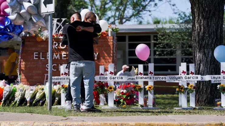 Dous homes abrazados diante da Robb Elementary School en Uvalde, Texas. Reuters