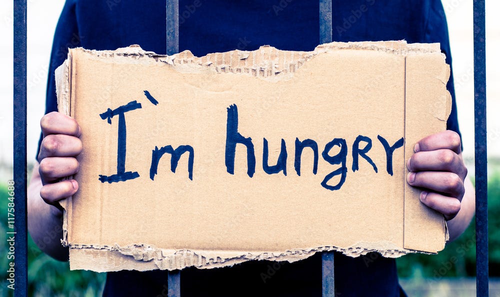 Teenager holds a sign on which is written in black marker, "I'm hungry."  Stock Photo | Adobe Stock