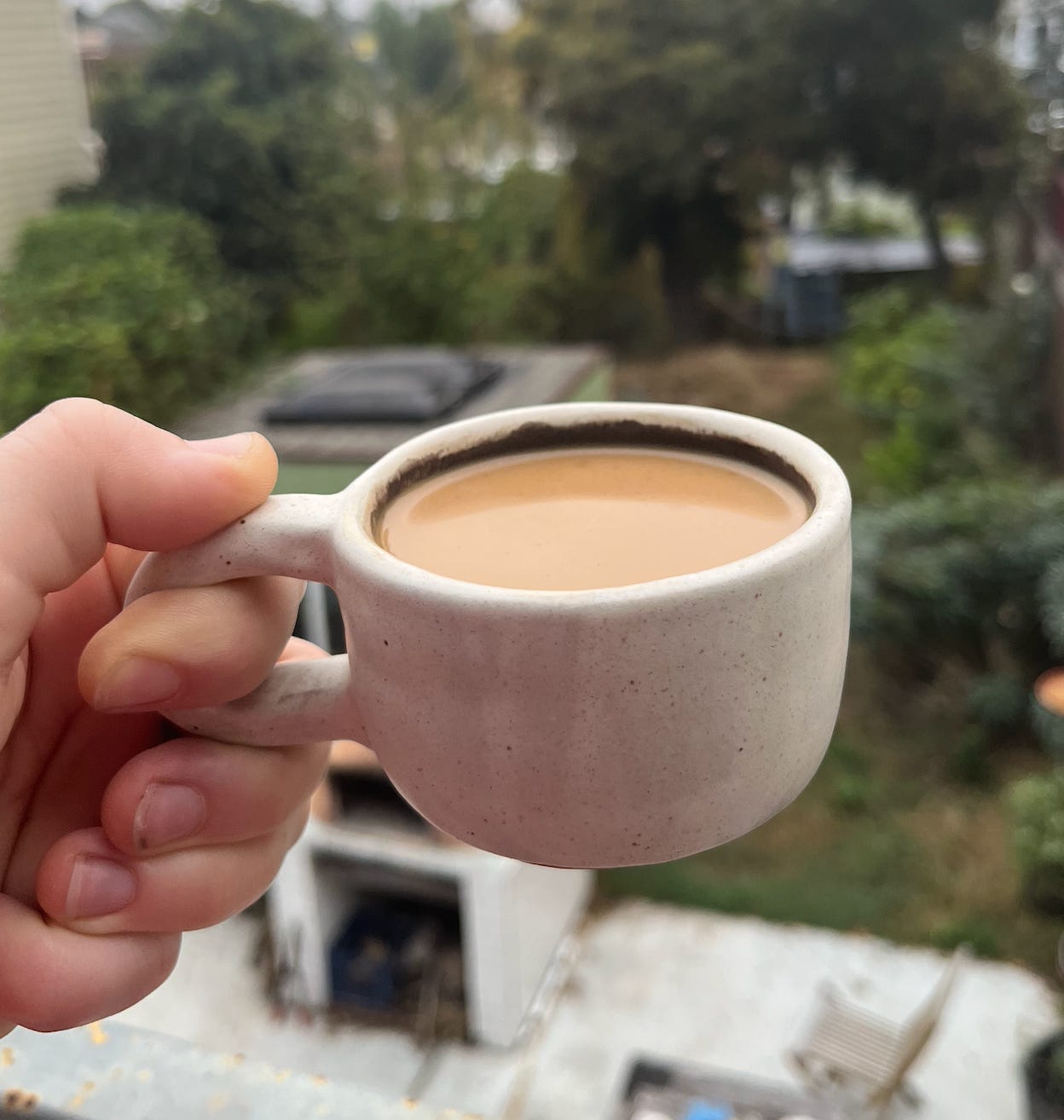 a hand holding a small handmade mug with coffee 