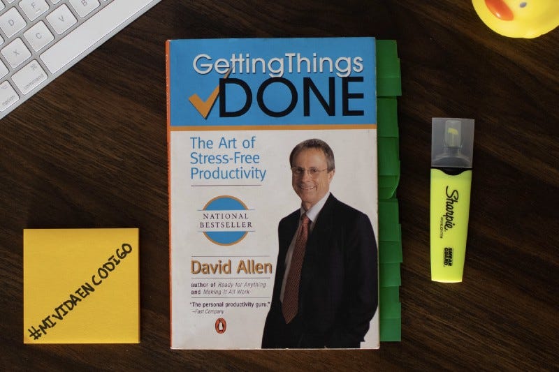 Una foto del libro Getting Things Done, con un resaltador del lado derecho y del lado izquierdo unos post-its con “#mividaencodigo” escrito.