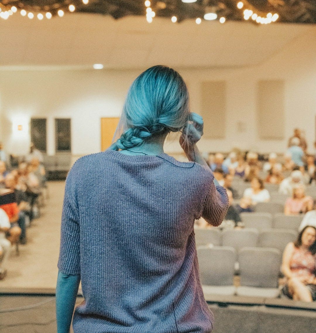 a woman with blue hair standing in front of an audience