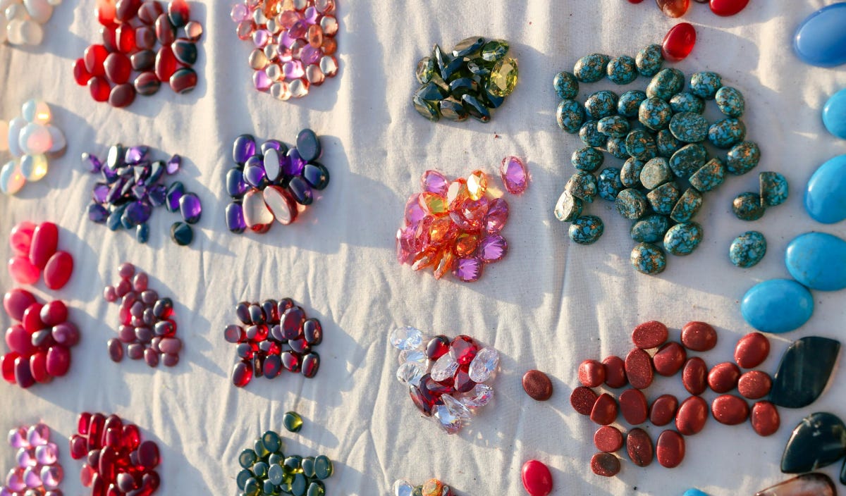 Piles of brightly colored semiprecious stones on a white cloth