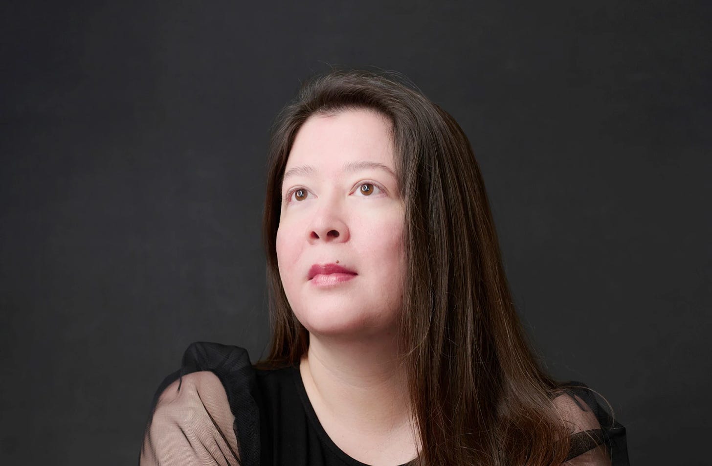 author photo of poet Karen Rigby, a woman with long brown hair wearing a black dress