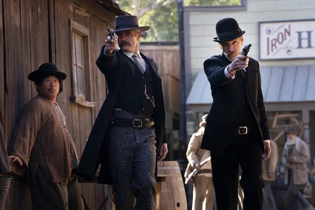 This image from 2019's Deadwood: The Movie sees three men standing in a Deadwood alleyway. From left to right: Unnamed Chinese immigrant, Marshal Seth Bullock (played by Timothy Olyphant), and hotelier Sol Star (played by John Hawkes).