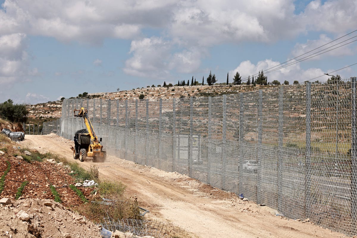 An Israeli transported moves sections of a fence as it's being erected around the Palestinian village of Sinjil, north of the occupied West Bank city of Ramallah on May 5, 2025. [Zain JAAFAR / AFP/ Getty Images]
