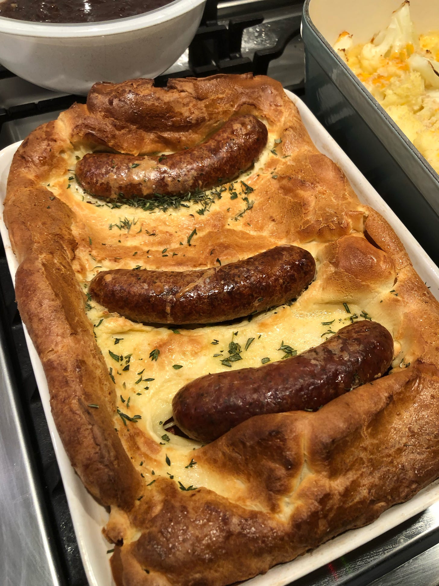 A fully-baked Toad in the Hole, sausages surrounded by puffy, browned Yorkshire pudding
