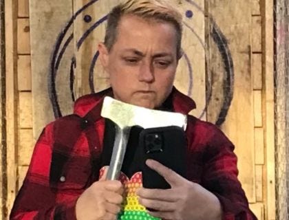 genderqueer person wearing flannel stares at axe