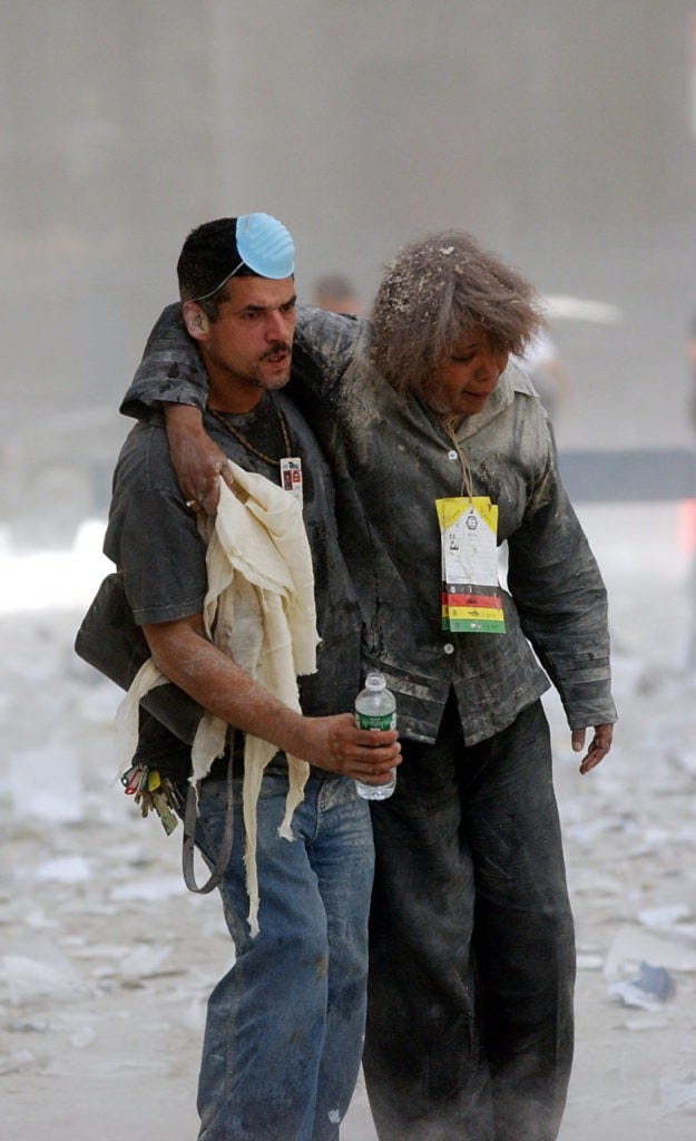 NEW YORK, UNITED STATES: A man helps evacuate a woman through rubble and debris after the collapse of one of the World Trade Center Towers 11 September 2001 in New York after two hijacked planes crashed into the landmark skyscrapers. AFP PHOTO/Stan HONDA (Photo credit should read STAN HONDA/AFP/Getty Images)