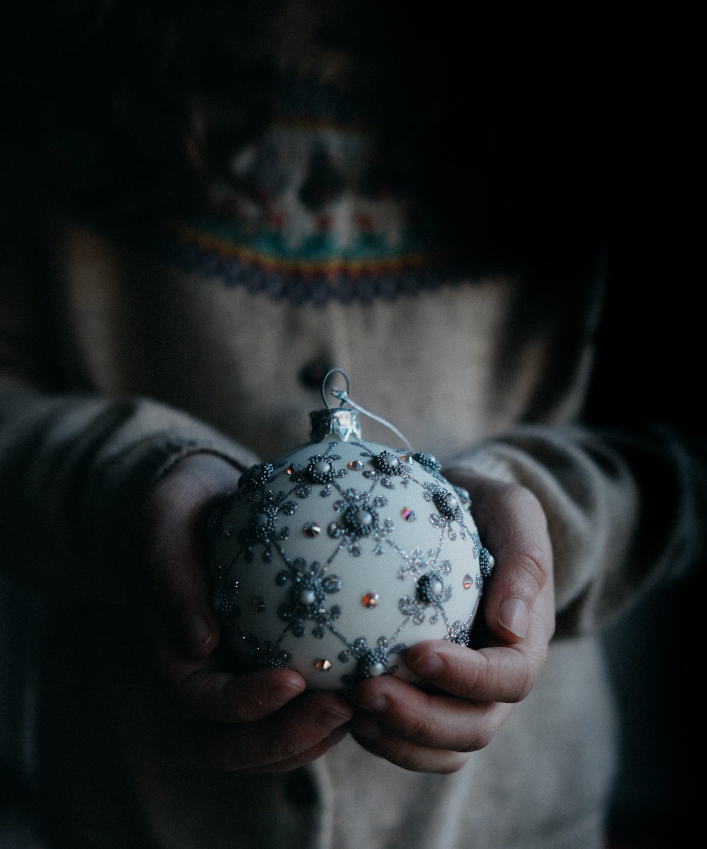 A person holds a beaded gray Christmas ornament