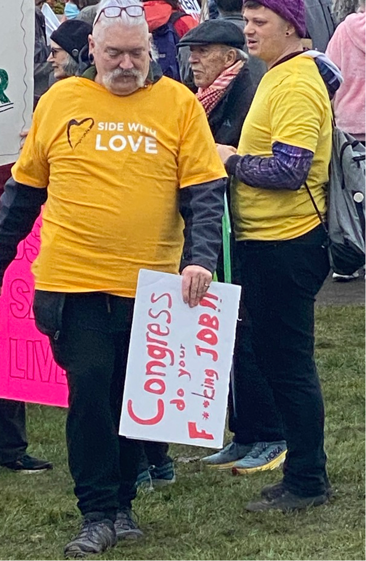 Olympia protestor sent mixed message between shirt slogan “Side with Love” and rally sign saying “Congress, do your F’n Job!!”