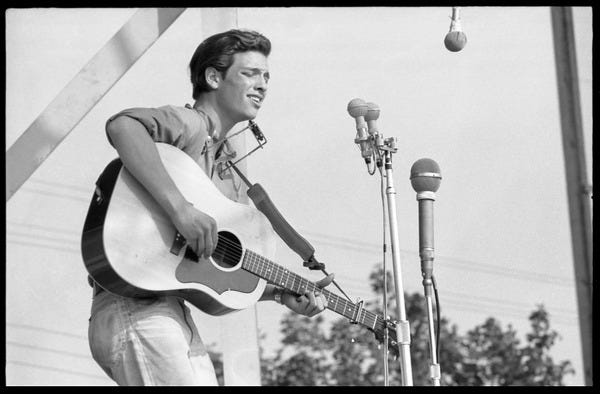 John Hammond (guitar and harmonica) performing on stage, Newport Folk Festival, July 28, 1963