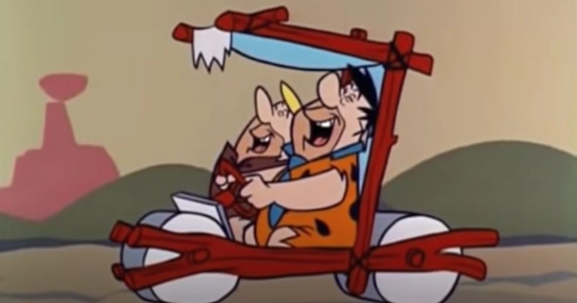 Fred Flintstone and Barney Rubble in the car on their way to "charge it!"