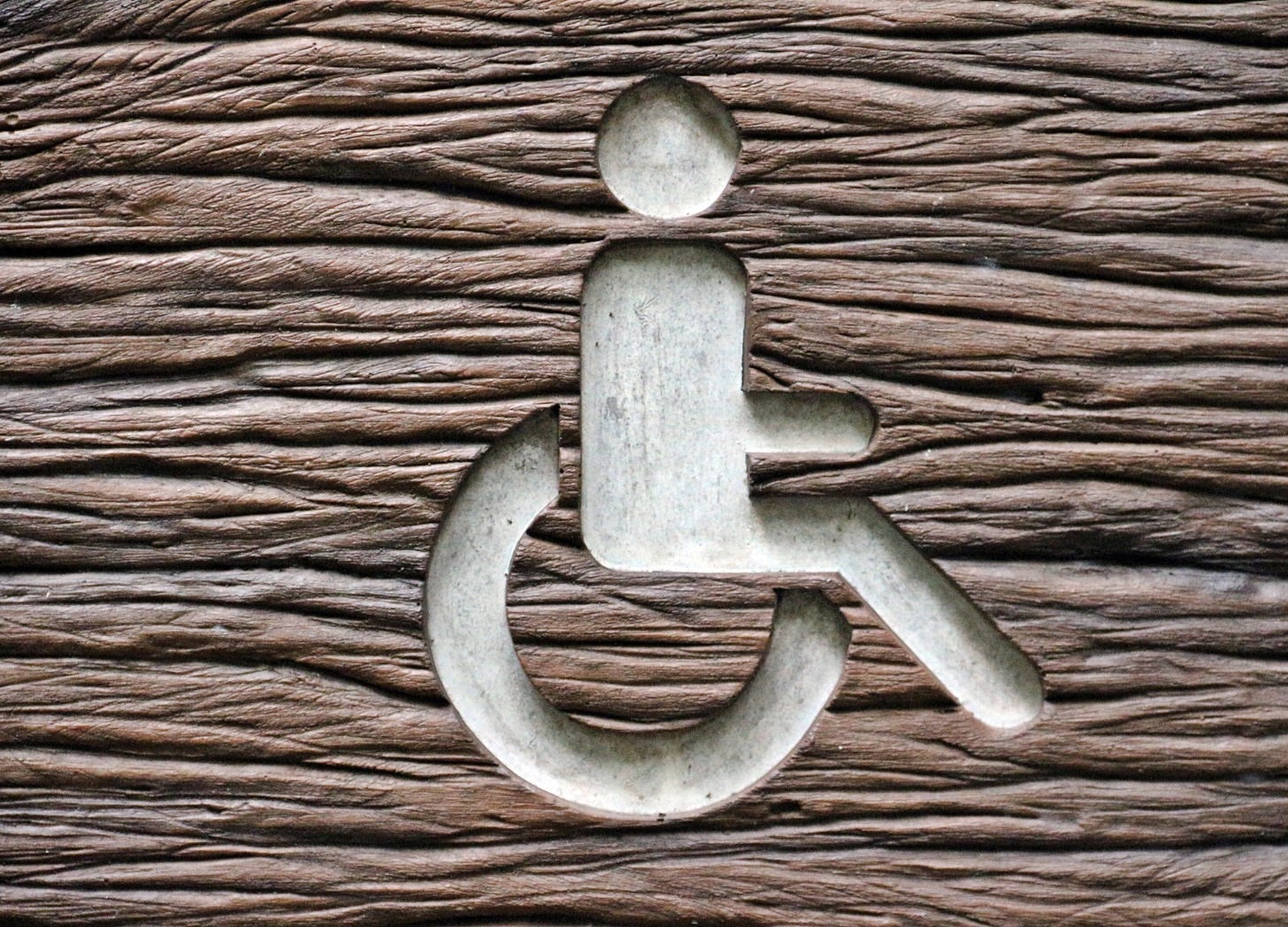 Wheelchair symbol carverd into textured wood