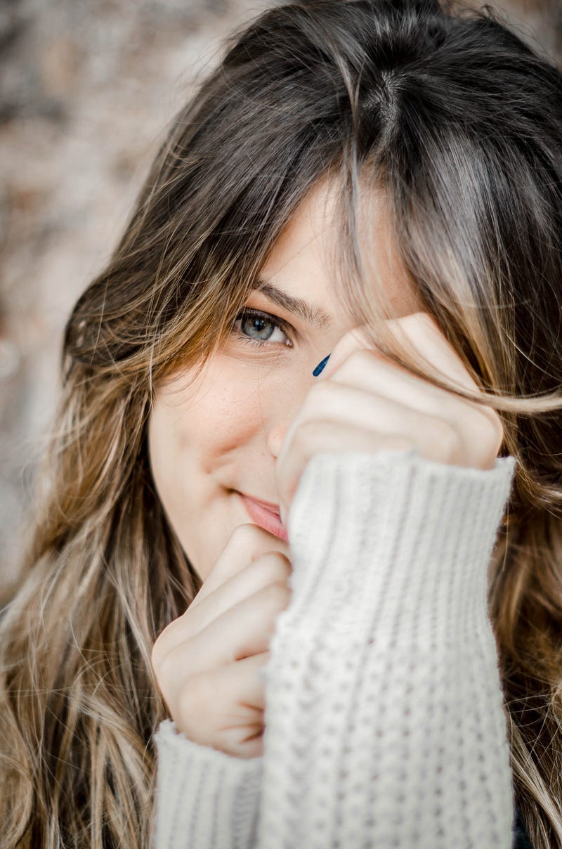 Shy girl with hands partially covering face