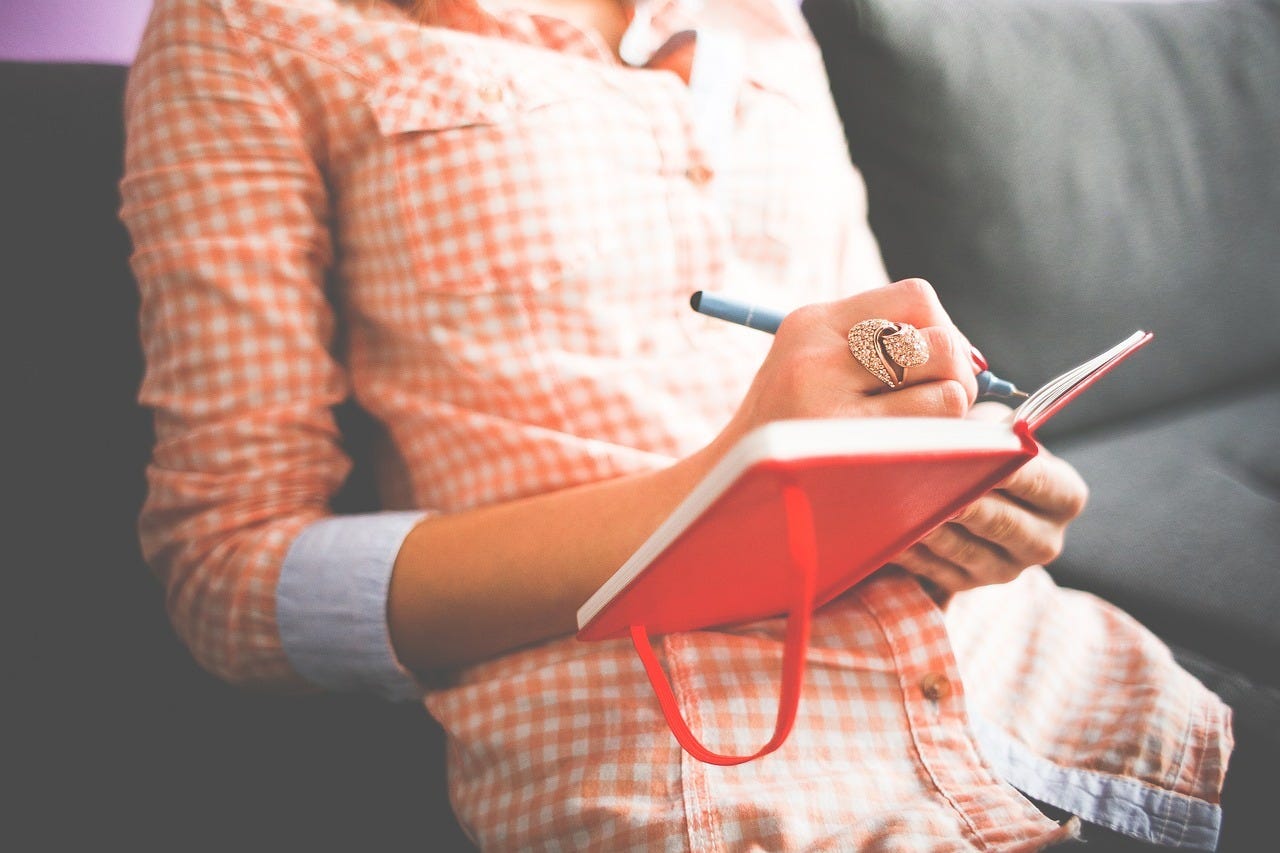 closeup on torso of woman writing in a journal