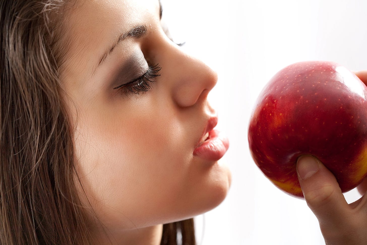 Woman holding apple close to her mouth