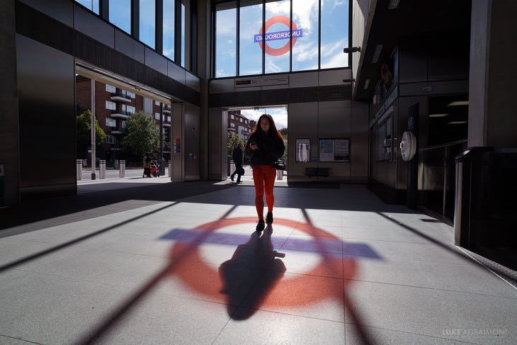 A young woman walking in the stained glass reflection of a tube roundel