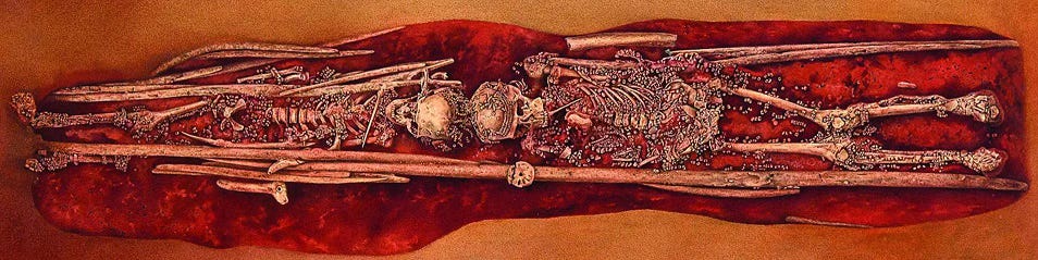 The skeletons of two children lying head to head. Both are covered in ivory beads and covered in ochre.