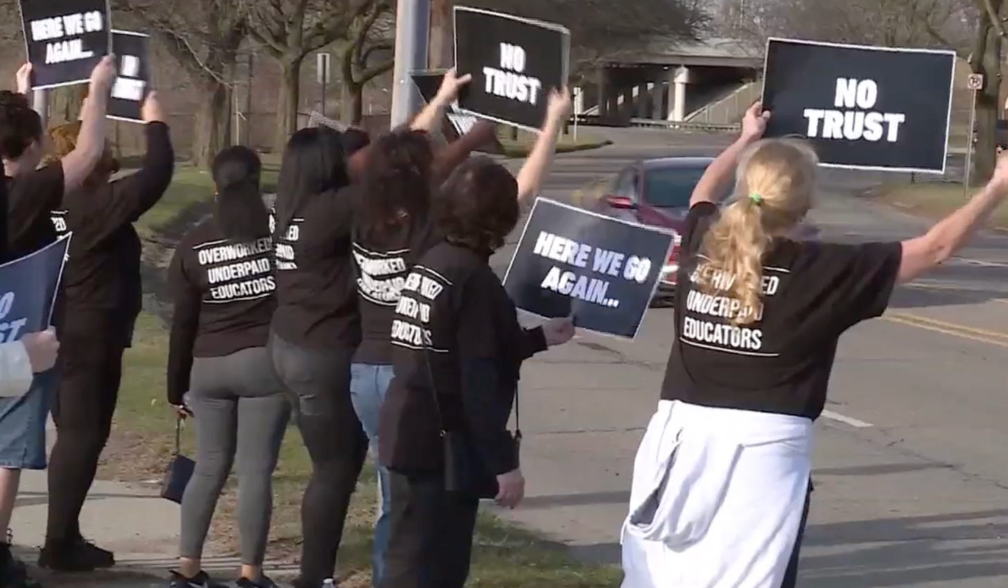 teachers in black t-shirts protesting the school board's decision to not give them raises
