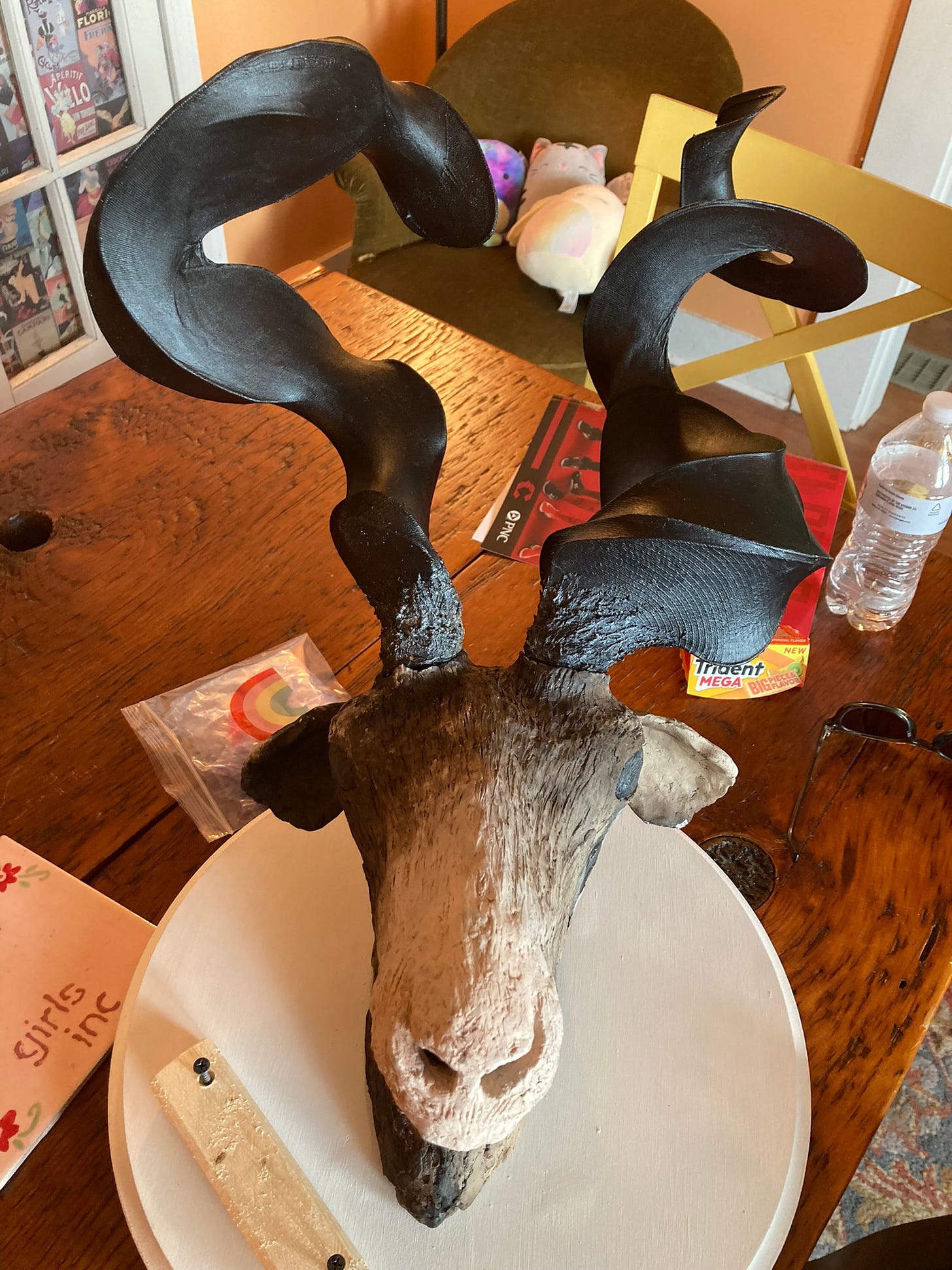 A ceramic antelope head with twisty, weird, black antlers