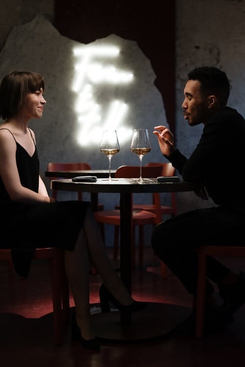 Free Couple enjoying a romantic evening with wine at a stylish cafe setting. Stock Photo