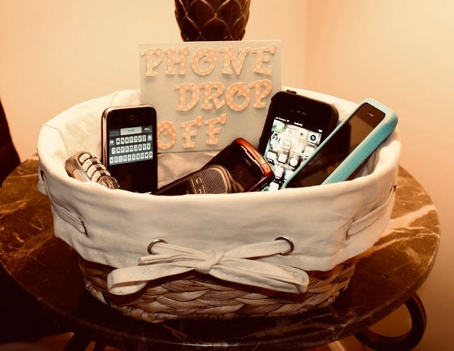 A woven basket of phones and a sign that says "phone drop off"