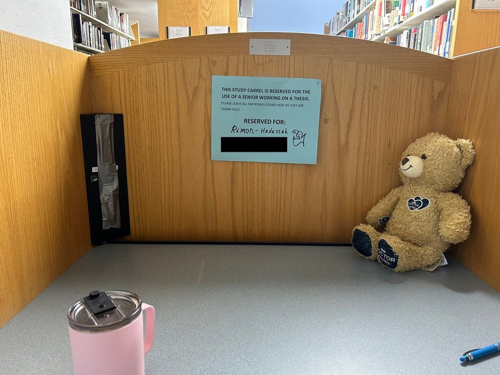 A library study carrel with a sign reserving it for Rimon-Hadassah. A Doctor Who Build-a-Bear is in the corner of the carrel.