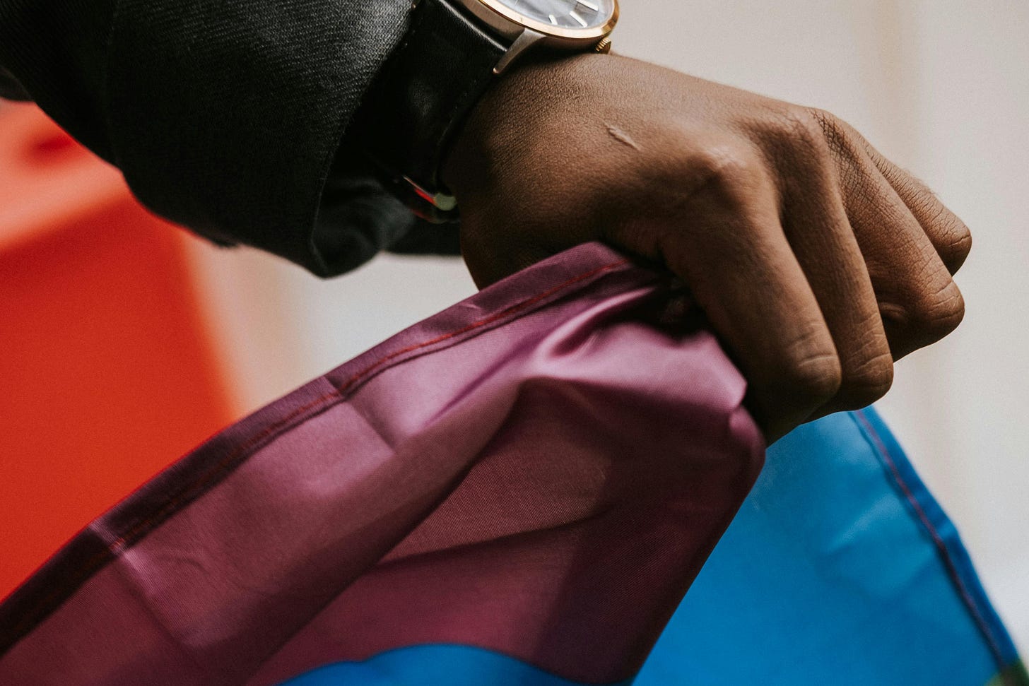 A hand grasps the edge of a Pride flag.