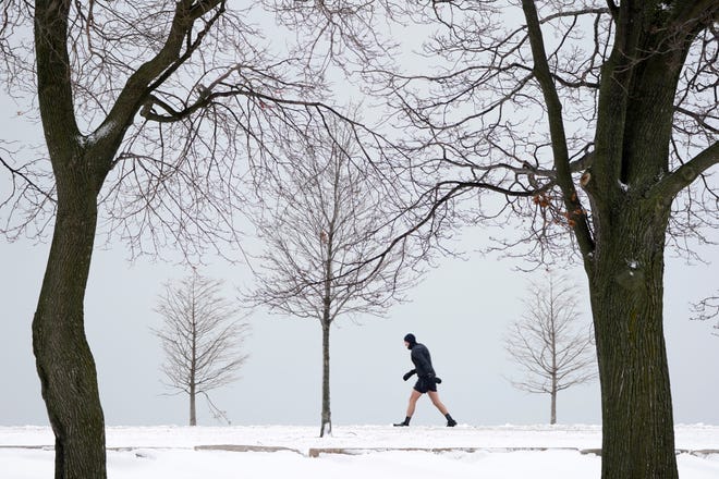 A lone runner leans into a stiff wind near Lake Michigan on the Northside of Chicago on Tuesday, Jan. 26, 2021.