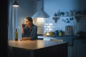 Portrait of Beautiful Lonely Young Woman Drinking from a Wine Glass in the Dark Kitchen. Depressed and Sad Adult Girl with Alcohol Problem Drinks Alone, Bad Relationships, Work Stress, Other Problems