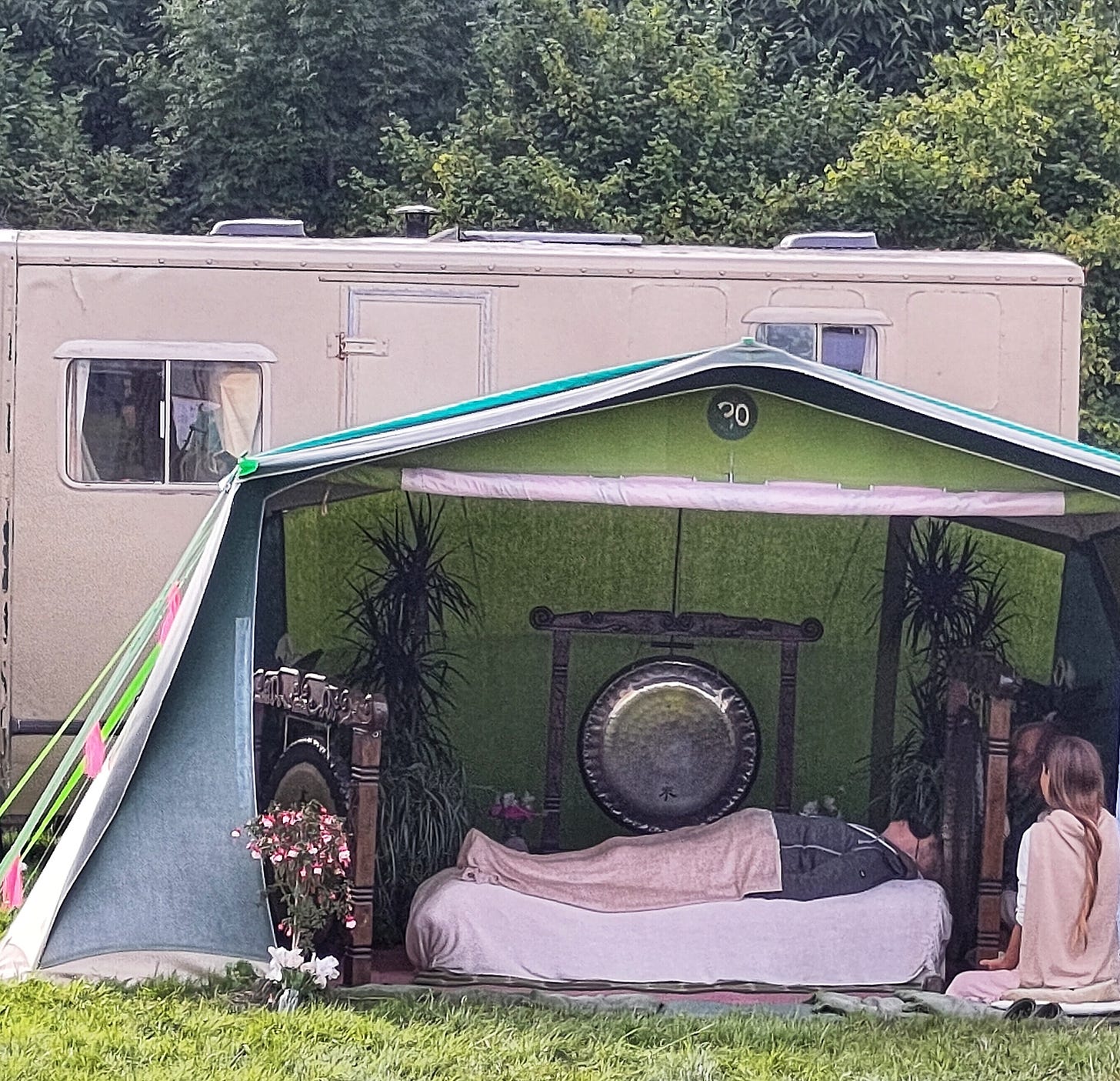 white woman lies blindfolded on bed; large gongs; gong bath; white woman long plait hair sits beside. 