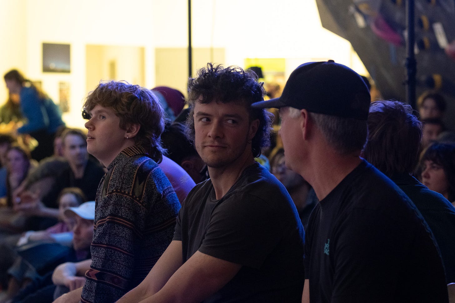 Two men look at eachother in conversation, seated in front of a crowd. Two men look at eachother in conversation, seated in front of a crowd.