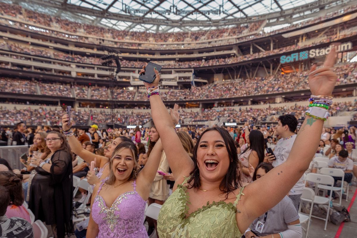 Fans with their arms raised in a crowded stadium.