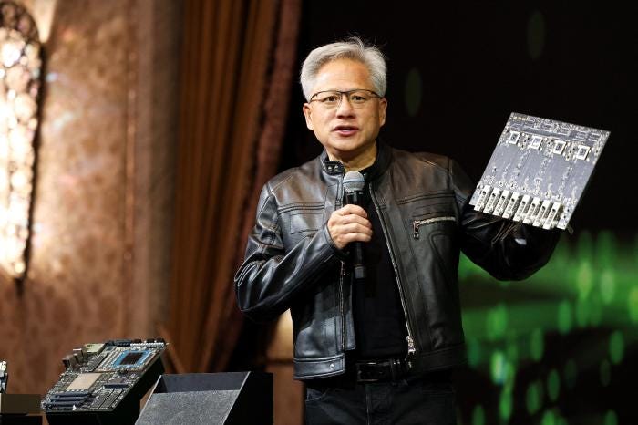 Jensen Huang of Nvidia speaking at a press conference, holding a circuit board.