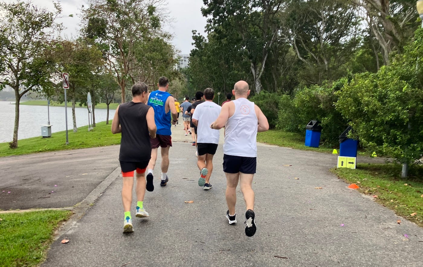 A group of runners on a wide path, tree-lined with the reservoir always on the left