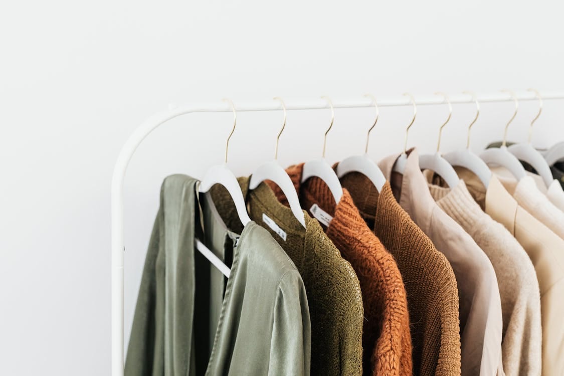 Free A minimalist display of colorful sweaters and shirts on white hangers. Stock Photo