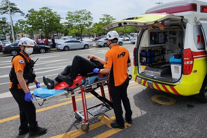 Rescue workers move a passenger on a stretcher to an ambulance at Daegu International Airport in Daegu, South Korea, Friday, May 26, 2023. A passenger opened a door on an Asiana Airlines flight that later landing safely at a South Korean airport Friday, airline and government officials said.