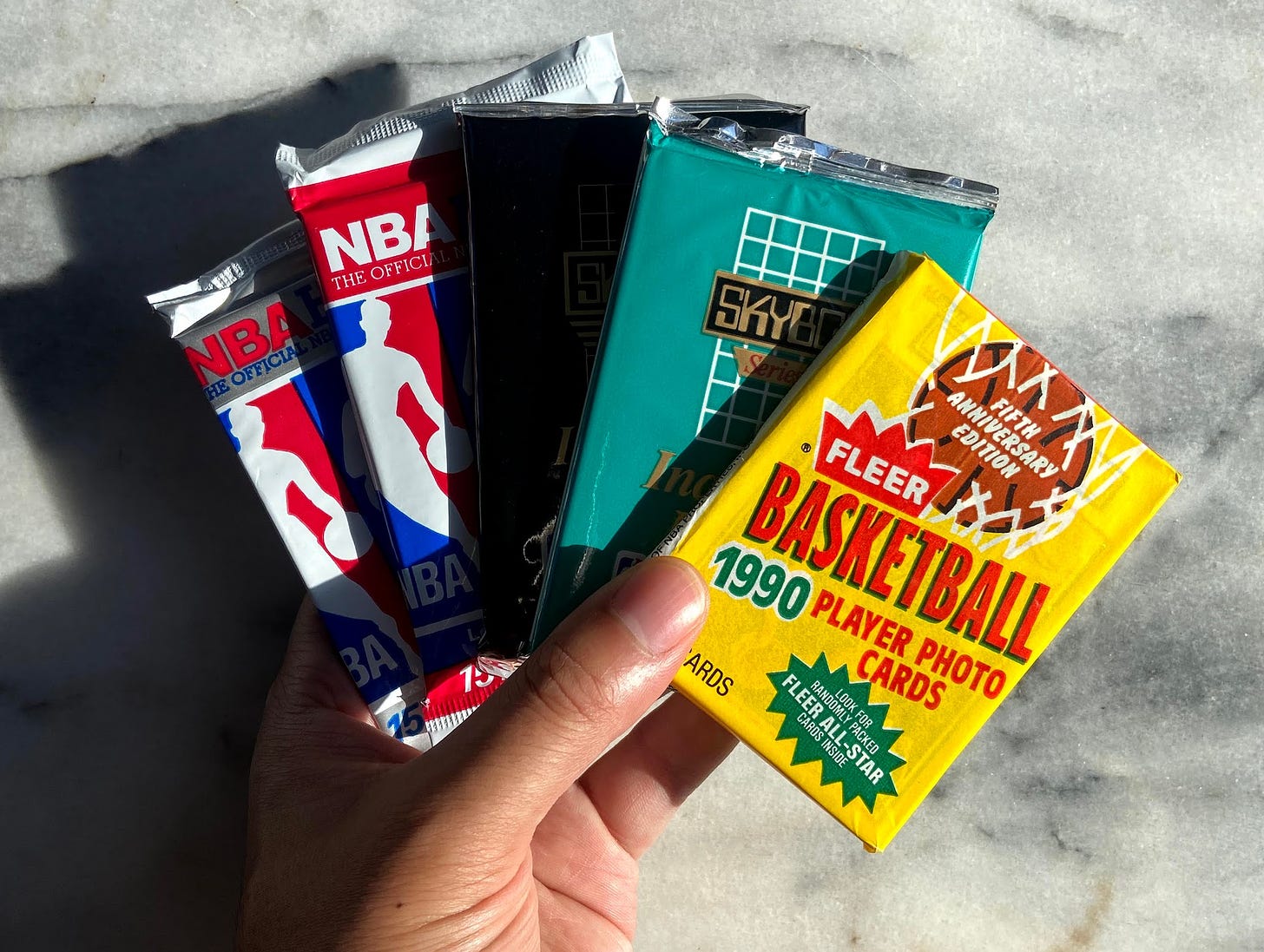 hand holding unopened packages of basketball cards from 1990