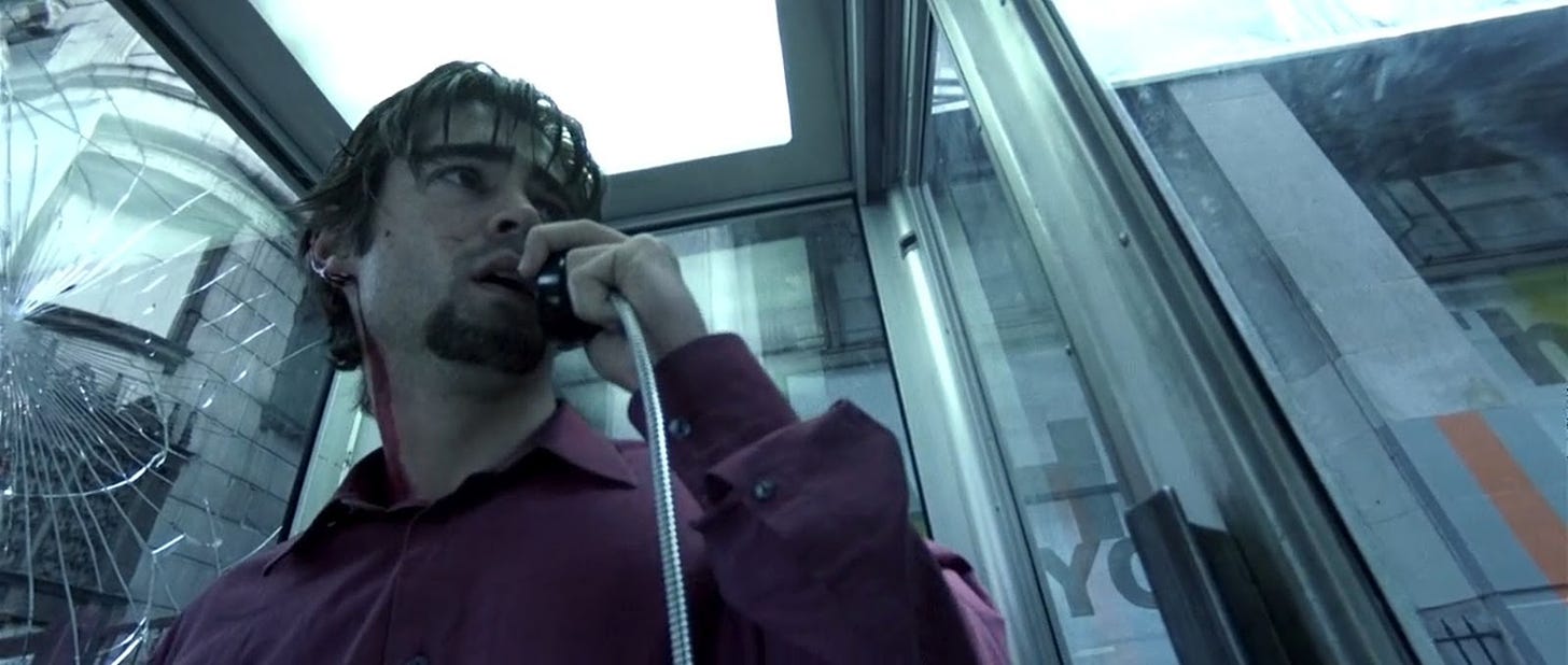 Man talks on the phone in a phone booth.