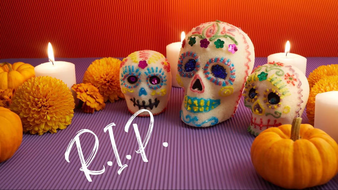 R.I.P. - a collection of sugar skulls, candles, pumpkins, and orange mums.