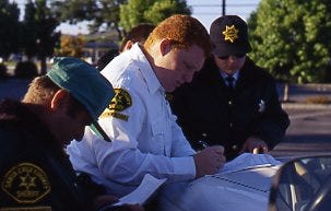 Three search-and-rescue volunteers in uniform examining paperwork prior to a search