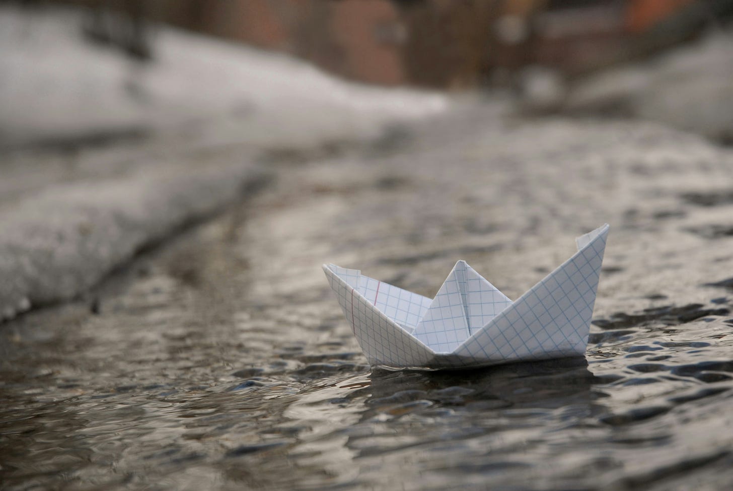 A photo of a paper boat floating on a flooded street