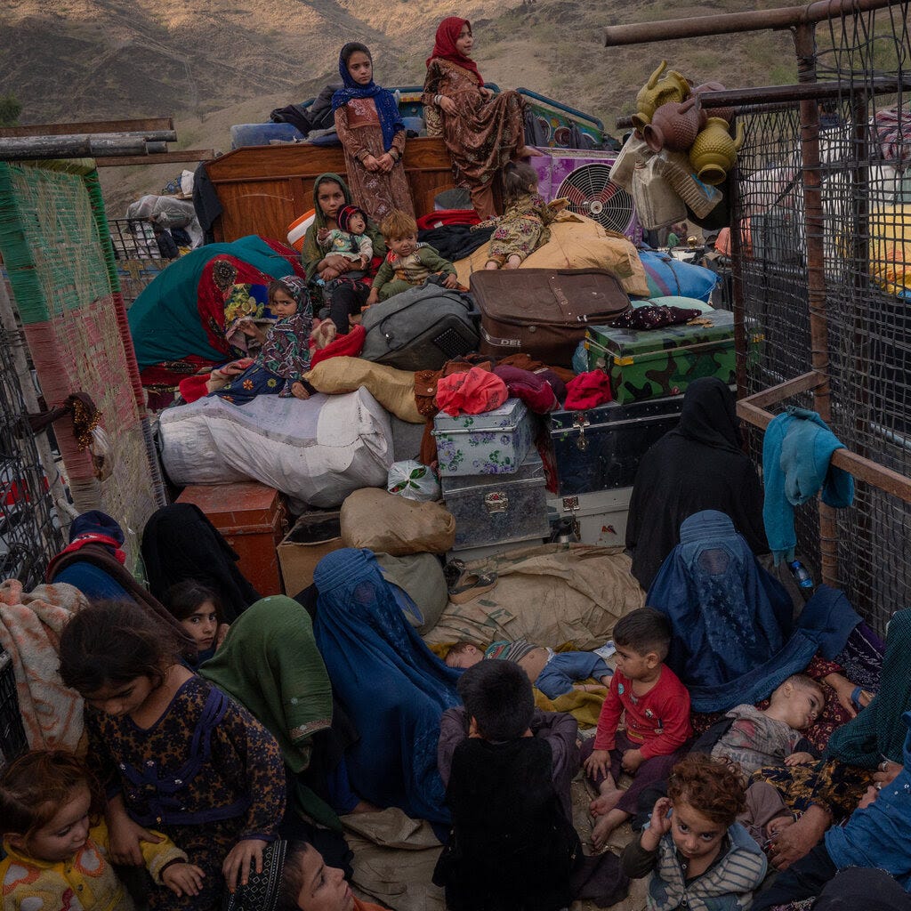 Afghan women and children surrounded by their belongings. 