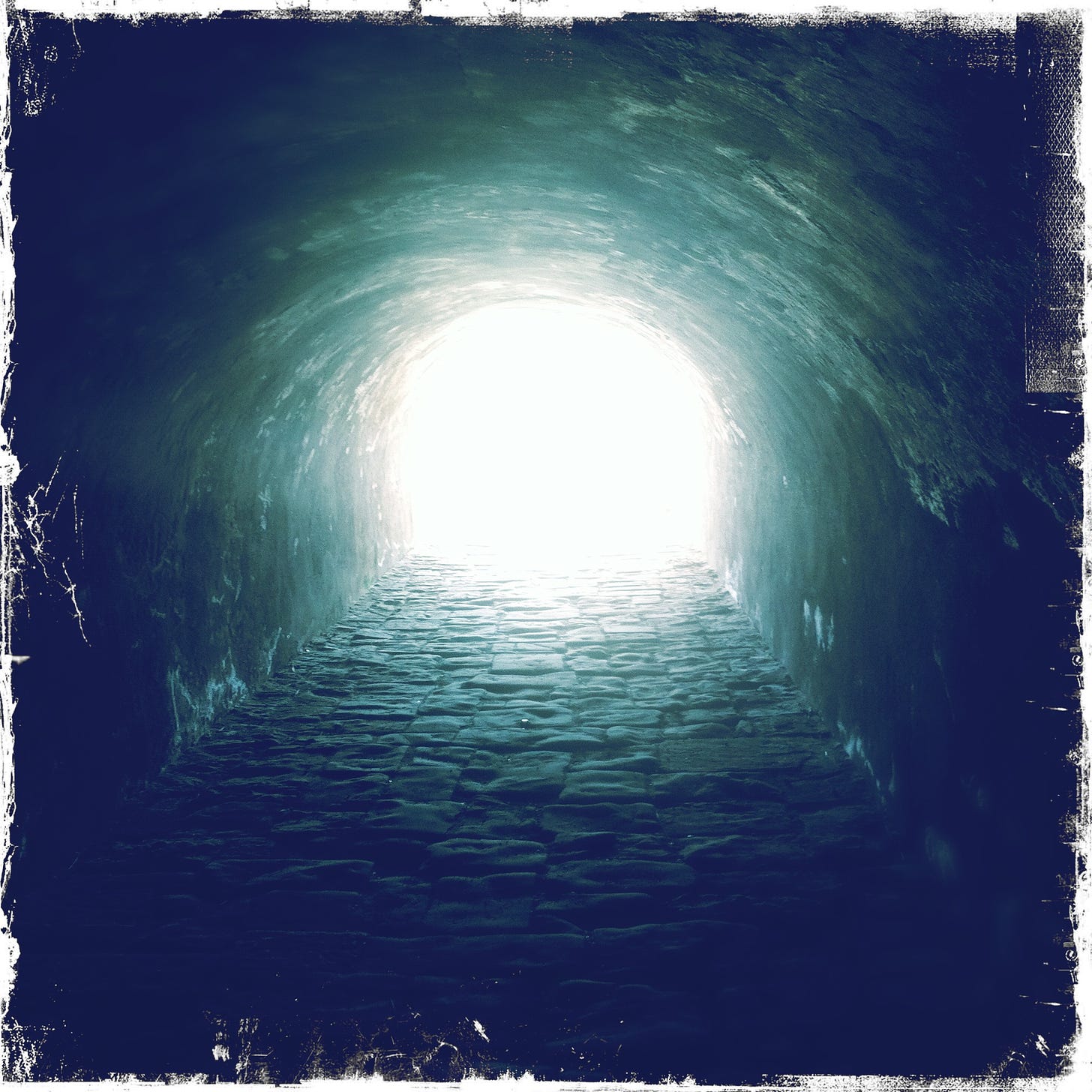 A cobbled tunnel and light.