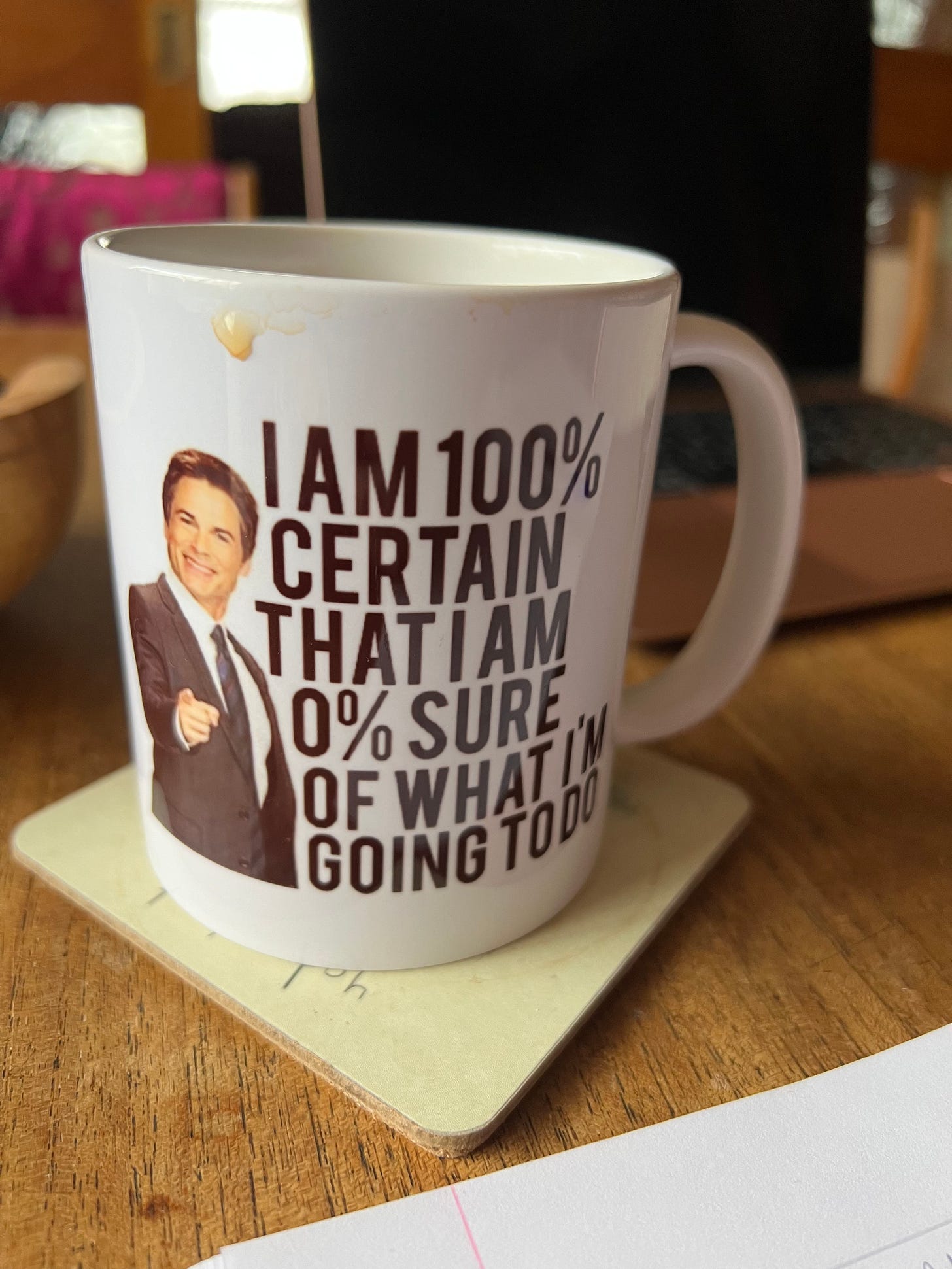 A white mug with a picture of a smiling man (Chris Traeger from Parks & Rec) and the phrase"I am 100% certain that I am 0% sure of what I'm going to do"